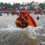 A devotee takes a dip as she worships the Sun god in the waters of the Arabian Sea during Chhath Puja in Mumbai
