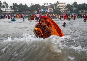 A devotee takes a dip as she worships the Sun god in the waters of the Arabian Sea during Chhath Puja in Mumbai