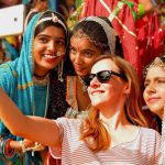 A foreign tourist takes selfies with Indian artists at Pushkar Camel Fair.