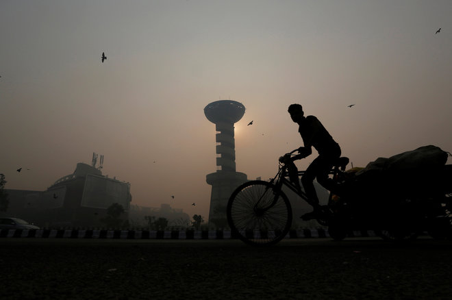 A rickshaw puller passes in front of a shopping mall amidst the heavy smog in New Delhi on October 31.