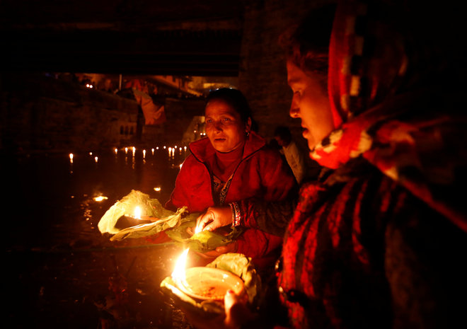 Devotees holding oil lamps perform religious ritual on the bank of Bagmati River flowing through the premises of Pashupatinath Temple, during the Bala Chaturdashi festival, in Kathmandu, Nepal, on November 28, 2016.