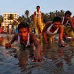 Devotees prostrate themselves in the sands near the Arabian Sea as they worship the Sun god during Chhath Puja in Mumbai