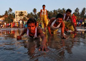 Devotees prostrate themselves in the sands near the Arabian Sea as they worship the Sun god during Chhath Puja in Mumbai
