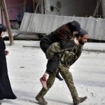 In this photo released by the Syrian official news agency SANA, a Syrian soldier carries a wounded woman in eastern Aleppo, Syria, on December 12, 2016.