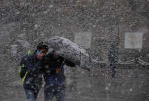 Pedestrians shelter under an umbrella as they walk through heavy snowfall on a road in Shimla on December 25, 2016