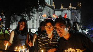 People lighting candles during Christmas Eve celebrations in front of St. Paul's Cathedral before Midnight Mass in Kolkata