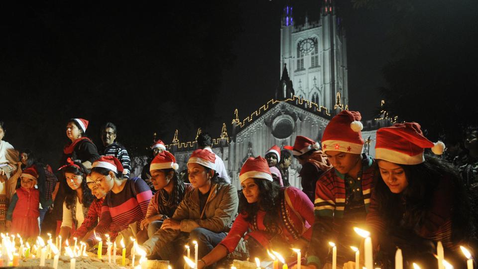 Peoples wearing Santa hats light candles during Christmas Eve celebration in front of St. Paul's Cathedral before Midnight Mass in Kolkata