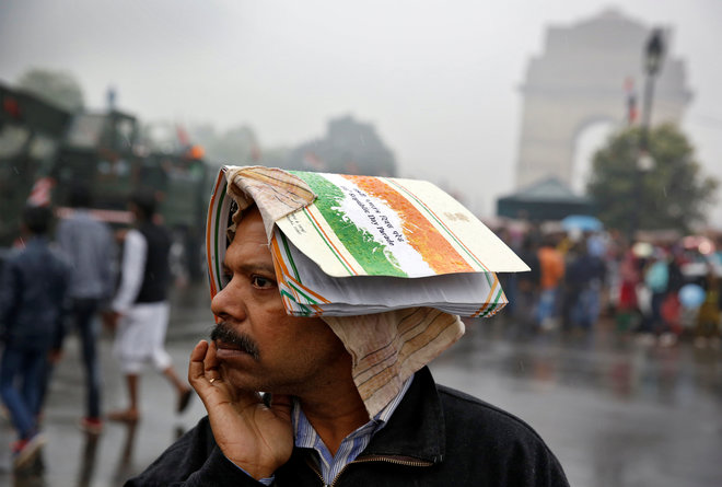 A man shelters from the rain at the India Gate following the Republic Day parade in New Delhi