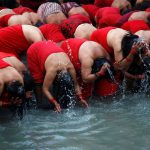 Devotees offer prayers before taking a holy bath in the Bagmati river at Pashupatinath Temple during the Swasthani Brata Katha festival in Kathmandu, Nepal