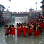 Devotees offer prayers before taking a holy bath in the Bagmati river at Pashupatinath Temple during the Swasthani Brata Katha festival in Kathmandu, Nepal