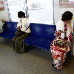 Japanese women wearing kimonos ride the train to attend the Coming of Age Day celebration ceremony at an amusement park in Tokyo, Japan