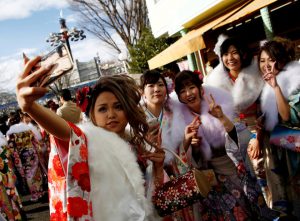 Japanese women wearing kimonos take a selfie after their Coming of Age Day celebration ceremony at an amusement park in Tokyo, Japan, on January 9