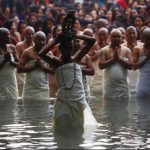 A devotee holds the statue of God Madhavnarayan while others offer prayer while performing rituals at River Saali.
