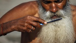 A Hindu holy man combs his beard in the courtyard of Pashupatinath temple in Kathmandu