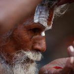 A Hindu holy man, or sadhu, applies tilak on his forehead