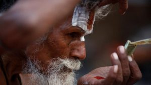 A Hindu holy man, or sadhu, applies tilak on his forehead