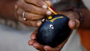 A Hindu holy man, or sadhu, paints Lord Shiva on the 'shaligram' stone as he sits at the premises of Pashupatinath Temple during the Shivaratri festival in Kathmandu, Nepal February 24, 2017