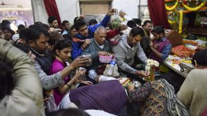 Devotees jostle for space as they offer garlands and prayers below the temple idol