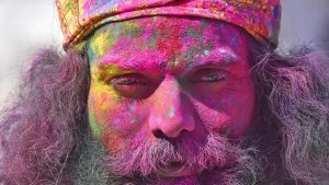 A Hindu devotee covered in coloured powder stands outside the Durgiana Temple