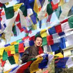 A Tibetan man ties prayer flags on a string during the ‘Losar’, or Tibetan New Year celebrations