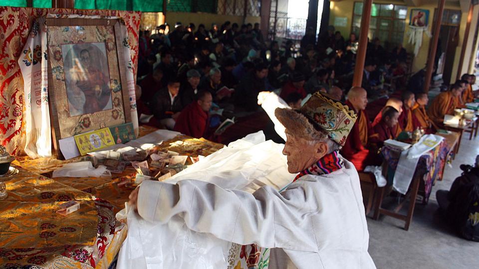 A Tibetan old man offering traditional white Khata (traditional Tibetan scarf) in front of Dalai Lama picture during special Morning Prayer session on the third and one of the most important day of the ‘Losar’