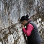 A Tibetan woman touches her head to the wall surrounding the residence of her spiritual leader the Dalai Lama on the third day of the Tibetan New Year called 'Losar' in Dharmsala