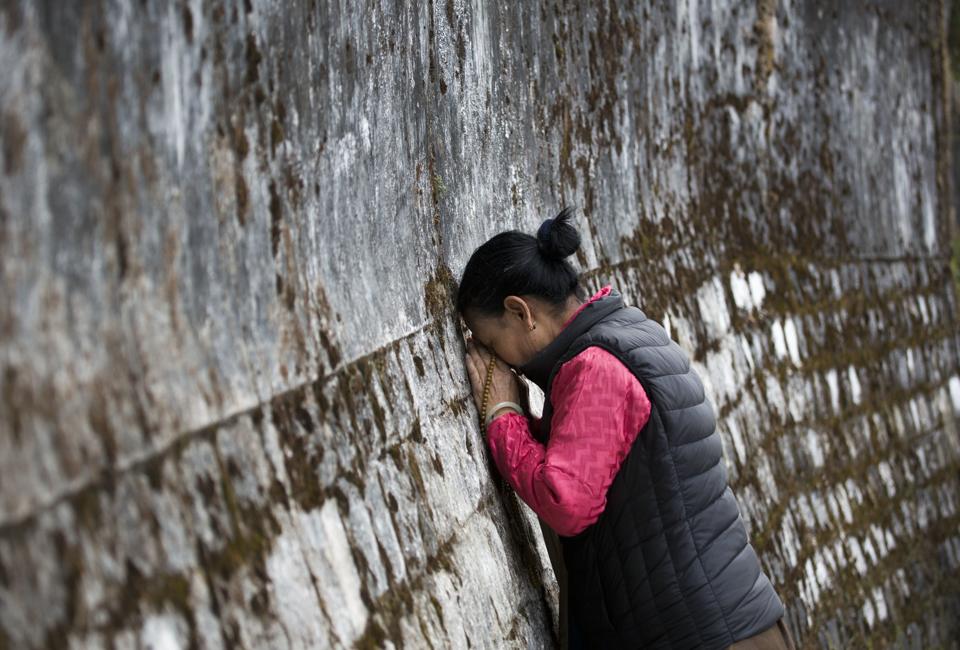 A Tibetan woman touches her head to the wall surrounding the residence of her spiritual leader the Dalai Lama on the third day of the Tibetan New Year called 'Losar' in Dharmsala