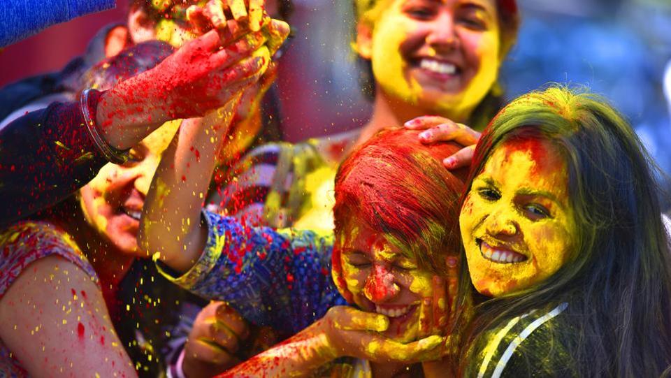 A college student reacts as coloured powder is thrown into her face during Holi in New Delhi