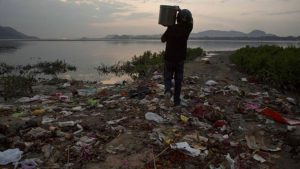 A devotee wearing a helmet carries flowers and other worship material before throwing them in the river Brahmaputra on the eve of World Water Day in Gauhati