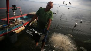 A fisherman carries a box of fishes at the Bancarios beach, ahead of World Water Day, in the Guanabara bay in Rio de Janeiro, Brazil
