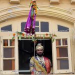 A man dressed in traditional attire watches the procession from his balcony in Girgaum