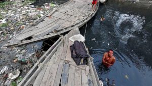 A man offers a prayer as he takes a dip in the polluted waters of Tolly's Nullah in Kolkata