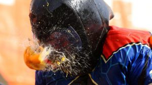 A member of a rival team is hit by an orange during an annual carnival orange battle