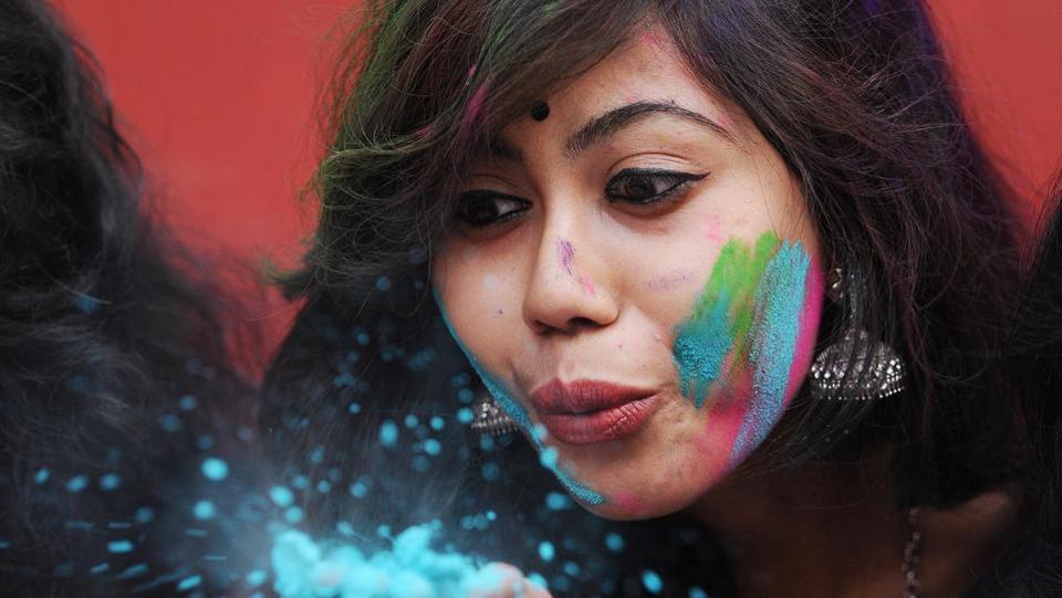 A student blows colour powder during Holi, celebrations inside the university campus in Kolkata, India