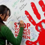 A student signs a poster to raise awareness about violence against women on International Women’s Day in the University of Jammu on March 8, 2017