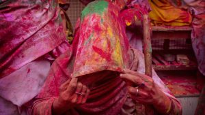 A widow smeared with colours covers her face during Holi celebrations, the arrival of spring festival, at the Gopinath temple in Vrindavan