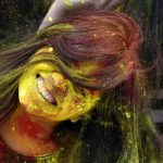 A woman shakes yellow gulal from her hair during Holi