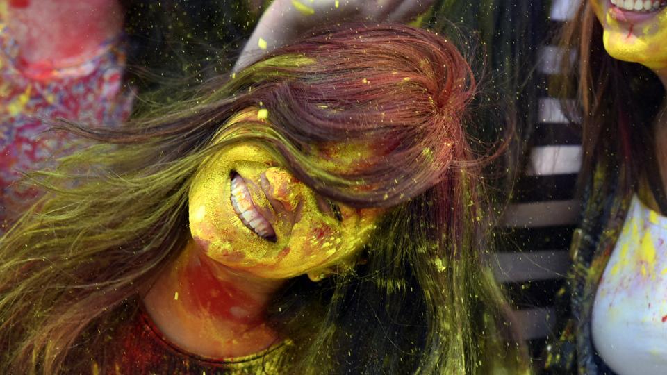 A woman shakes yellow gulal from her hair during Holi