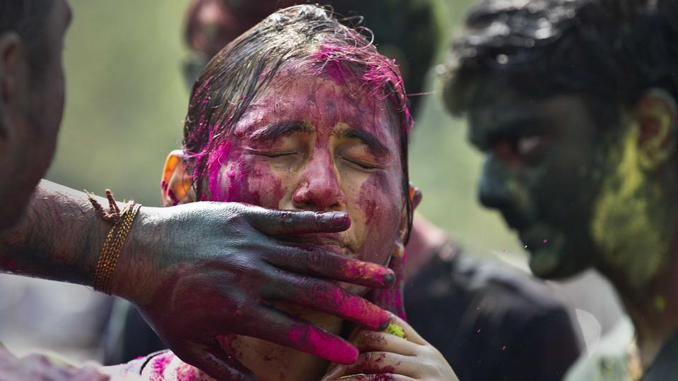 A woman shuts her eyes as coloured powder is smeared on her face during Holi celebration in Guwahati