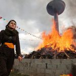 A woman walks past a bonfire during a gathering celebrating Newroz. This weekend, Turkey responded with fury after tens of thousands of people attended a pro-Kurdish protest in Germany, many brandishing Ocalan flags and pro-PKK insignia. But only a few portraits of Ocalan could be seen at the Diyarbakir rally