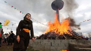 A woman walks past a bonfire during a gathering celebrating Newroz. This weekend, Turkey responded with fury after tens of thousands of people attended a pro-Kurdish protest in Germany, many brandishing Ocalan flags and pro-PKK insignia. But only a few portraits of Ocalan could be seen at the Diyarbakir rally