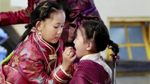 A young Tibetan girl dressed up in traditional attire helps her younger sister get ready on the occasion of the Tibetan New year