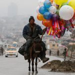 An Afghan man rides on his donkey, holding balloons for sale during Newroz Day celebrations, a festival marking their spring and new year, in Kabul, Afghanistan