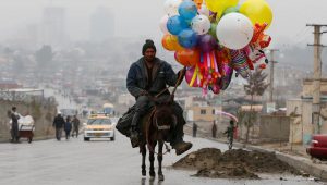 An Afghan man rides on his donkey, holding balloons for sale during Newroz Day celebrations, a festival marking their spring and new year, in Kabul, Afghanistan