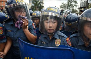 Policewomen holding truncheons stand guard as women’s group Gabriela hold a rally to celebrate International Women’s Day near the US embassy in Manila on March 8, 2017
