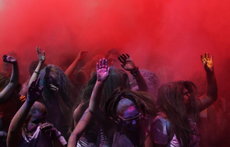 Revelers dance after throwing colored powders in the air.