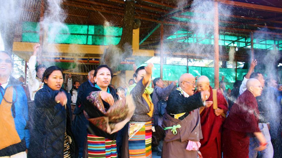 Tibetans throw white flour powder in air during a prayer session as part of ‘Losar’ celebration