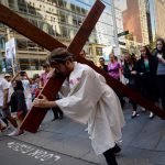 25-year-old student Brendan Paul depicting himself as Jesus Christ carries a cross in a re-enactment from the bible, on Good Friday in Sydney. They normally fast on this day unless they have health issues or are below the prescribed age