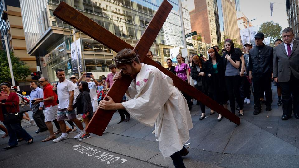 25-year-old student Brendan Paul depicting himself as Jesus Christ carries a cross in a re-enactment from the bible, on Good Friday in Sydney. They normally fast on this day unless they have health issues or are below the prescribed age