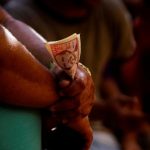 A cockfighting enthusiast holds money during a fight at the arena